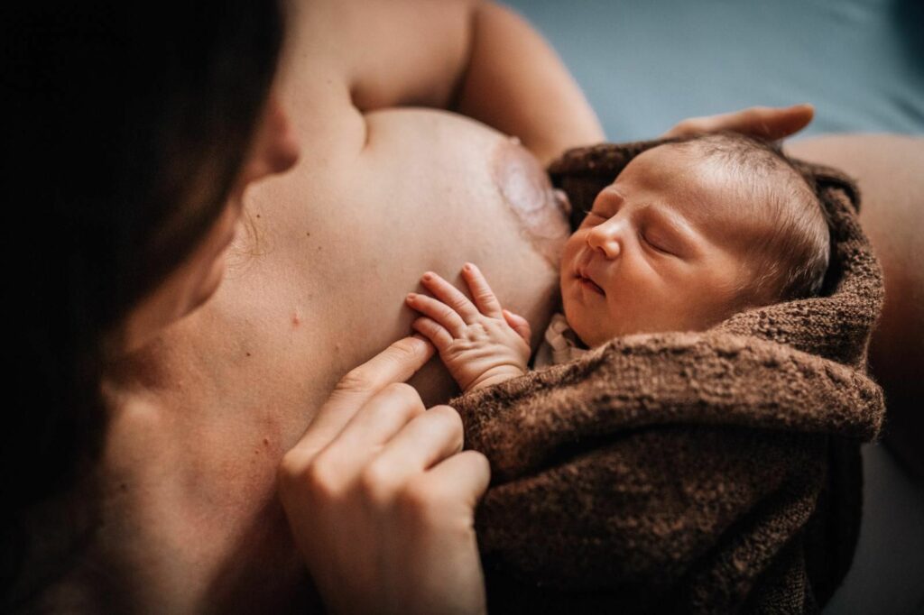 Mama hält Neugeborenes im Arm - Geburtsfotografie Kärnten