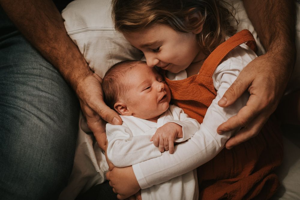 Große Schwester liebkost Baby - Babyfotos, Neugeborenenfotos, Neugeborenenshooting Klagenfurt