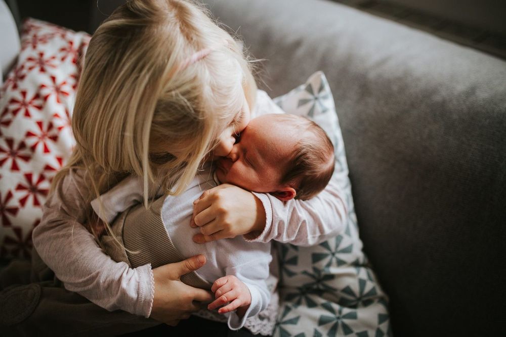 Große Schwester küsst Baby - Babyfotos, Neugeborenenfotos, Neugeborenenshooting Klagenfurt