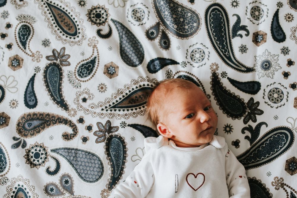 Neugeborenes liegt auf einer gemusterten Decke - Babyfotos, Neugeborenenfotos, Neugeborenenshooting Klagenfurt